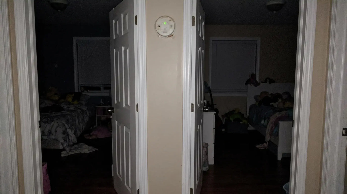 Standard detector glowing green outside dark bedroom doors